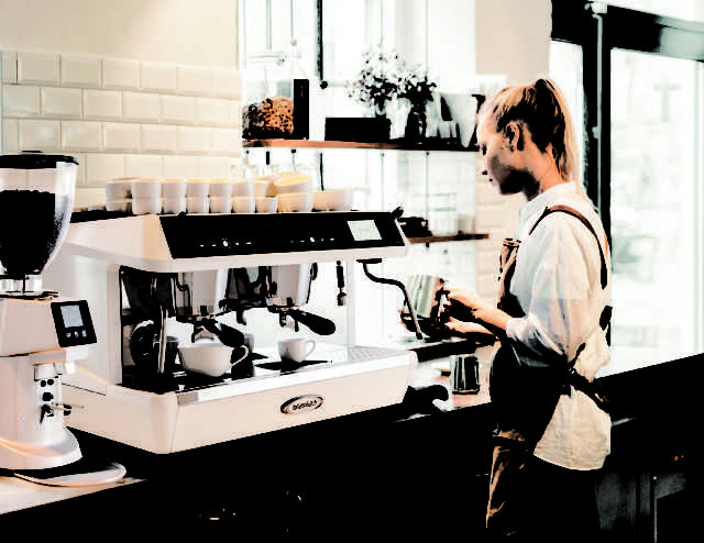 Female barista using coffee machine at cafe