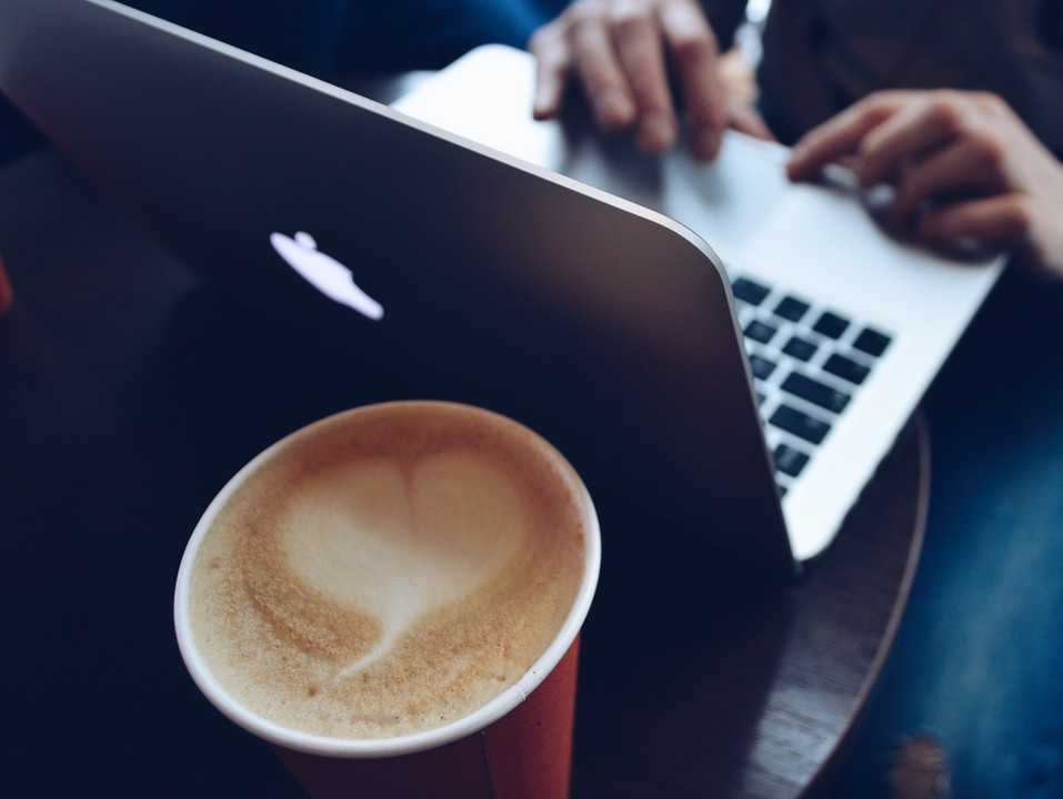 Una classica immagine di una caffetteria Strabucks: computer e cappuccino con tanto di latte art